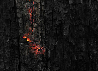Dark black background of burnt wood with red hot embers still burning. - 415506697