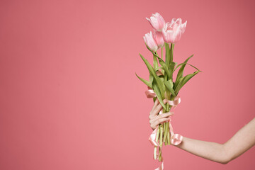 a bouquet of flowers in the hands of a woman pink background