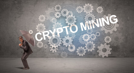 Businessman defending with umbrella from CRYPTO MINING inscription, technology concept