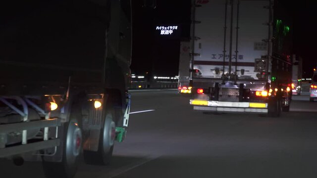 深夜の新東名高速道路をを走行する何台もの大型トラック