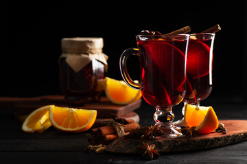 mulled wine with spices poured into glass glasses on a wooden dark background, place for text