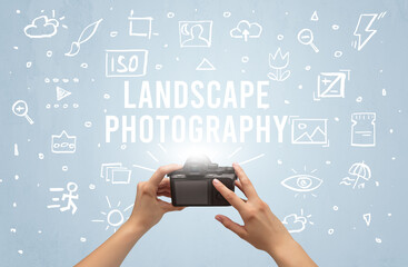 Hand taking picture with digital camera and LANDSCAPE PHOTOGRAPHY inscription, camera settings concept