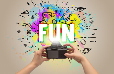 Close-up of a hand holding digital camera with abstract drawing and FUN inscription