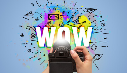 Close-up of a hand holding digital camera with abstract drawing and WOW inscription