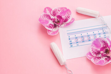 Menstruation. Calendar, tampons, orchid flowers on a pink background.