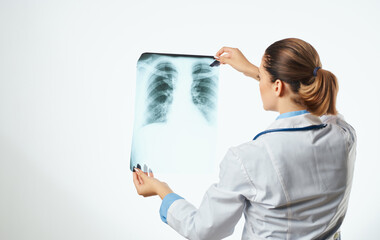 Woman doctor examines x-ray and medical gown glasses with stethoscope