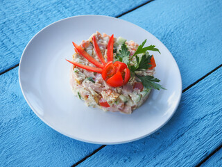 Olivier salad on a blue wooden background