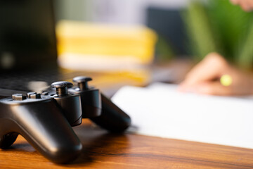 Close up Selective focus on joystick , Kid busy reading in background in front of gamepad - concept of kids gaming and education. © WESTOCK
