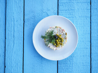 Olivier salad on a blue wooden background
