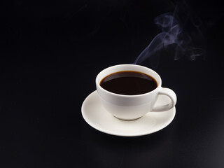 A cup of hot black coffee on black background with hot steam