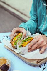 Man's hands holding big portion sandwich outside. Healthy food concept, close up, food photography concept, from above