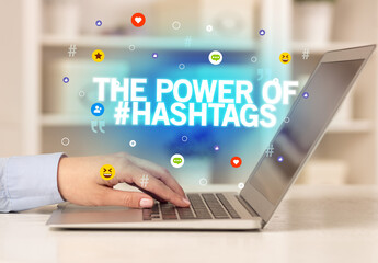 Freelance woman using laptop with THE POWER OF #HASHTAGS inscription, Social media concept