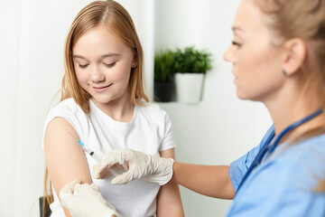 woman doctor giving a girl an injection in the arm vaccination