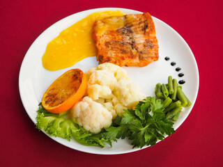 Baked salmon in foil on a red background