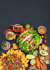 Hispanic mexican food, nachos, guacamole, meat tacos on dark background