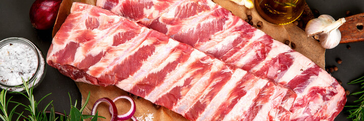 Fresh raw pork ribs seasoned with spices on dark background. © bit24