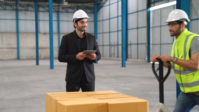 Factory workers deliver boxes package on a pushing trolley in the warehouse . Industry supply chain management concept .