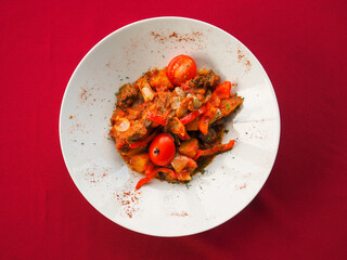 Beefsteak with tomato and herbs on a red background