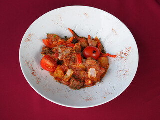 Beefsteak with tomato and herbs on a red background