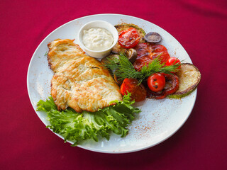 Beefsteak with tomato and herbs on a red background