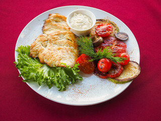 Beefsteak with tomato and herbs on a red background
