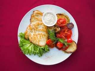 Beefsteak with tomato and herbs on a red background