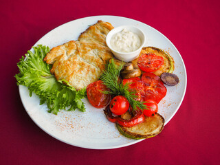 Beefsteak with tomato and herbs on a red background