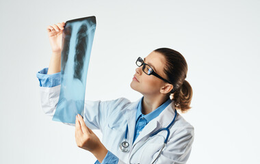 Woman doctor examines x-ray and medical gown glasses with stethoscope