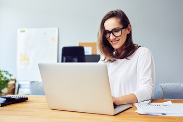 Happy young woman working with laptop at home