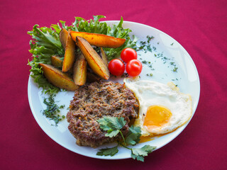 Beefsteak with tomato and herbs on a red background