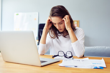 Stressed young woman sitting at desk working from home office