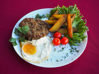 Beefsteak with tomato and herbs on a red background
