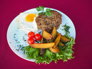 Beefsteak with tomato and herbs on a red background