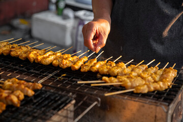Meat skewers cook over hot coals in Satay Street food market