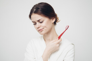 woman in a robe With a toothbrush in her hand morning procedures