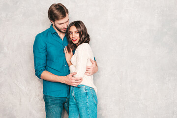 Portrait of smiling beautiful woman with red lips and her handsome boyfriend. Happy cheerful family posing in studio near gray wall.Valentine's Day. Models hugging. Concept of love