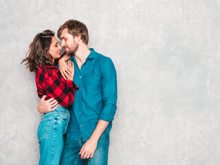 Hot beautiful woman and her handsome boyfriend. Models posing near gray wall in jeans clothes. Young passionate couple hugging before having sex. Sensual pair getting closer for kiss. Lover couple