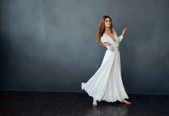Charming lady in a white dress on a gray background dance gesticulating with her hands Copy Space...