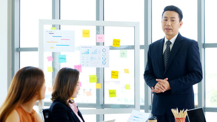 Businessman presenting business plan information to team at office meeting, Asian leader man...