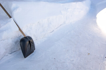 Snow shovel. Winter background. A snow shovel stands next to a pile of snow. To rake paths in winter.