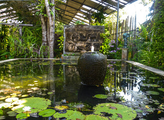 Stone fountain in the middle of the ornamental fish basin.