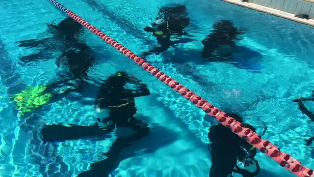 Group of unrecognizable scuba divers exercising an underwater scuba diving in a swimming pool.
