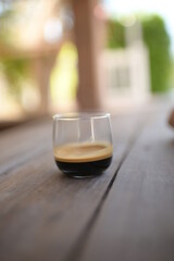 espresso shot in small curve glass on wood table vintage style