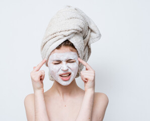 woman with a white mask against black dots on her face and a towel on her head