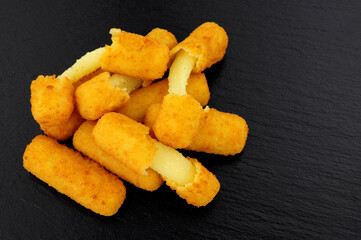 Group of breadcrumb covered mozzarella cheese sticks on a slate stone background