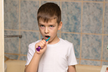 a boy of six is brushing his teeth in the bathroom. close-up portrait