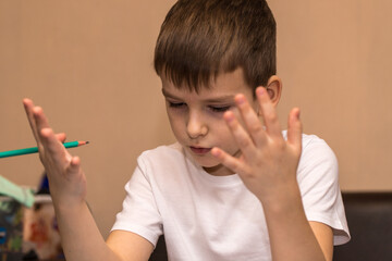 a six-year-old boy solves a math example with his fingers. close-up