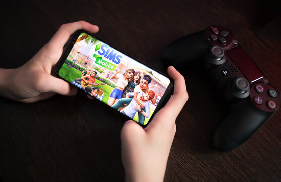 Los Angeles, California, USA - February 21, 2021: Boy holds the phone with The Sims Mobile on the display screen