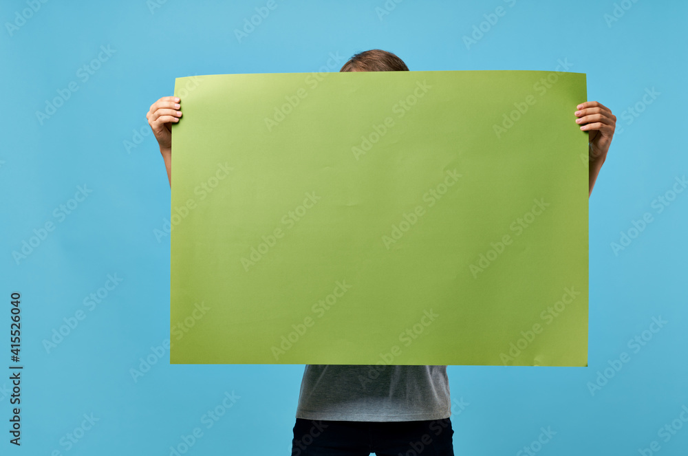 Wall mural man holding green banner marketing copy space blue advertising background