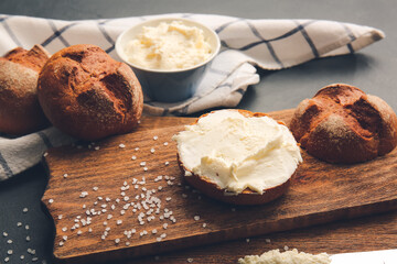 Bun with tasty cream cheese on dark background
